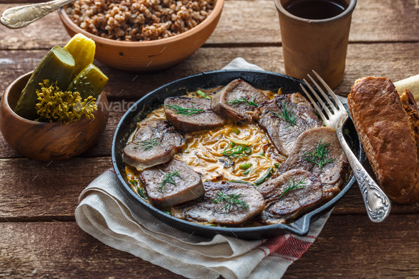 Beef tongue in cast iron skillet with cream sauce, rustic style. Stock Photo by fazeful
