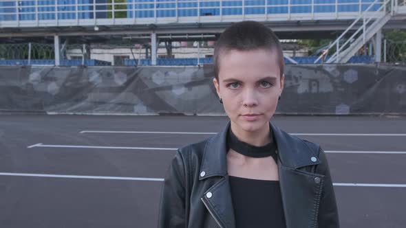 Portrait of Smiling Young Woman with Short Hair in Industrial City Background at Sunset alt