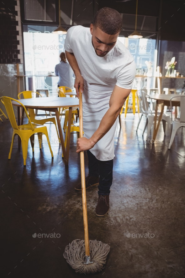 Waiter mopping floor in cafe