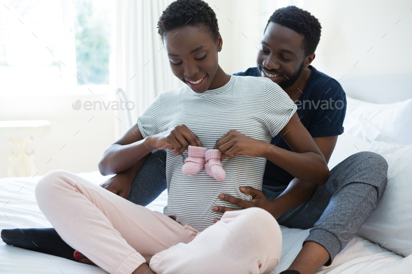Couple holding baby socks in bedroom - Stock Photo - Images
