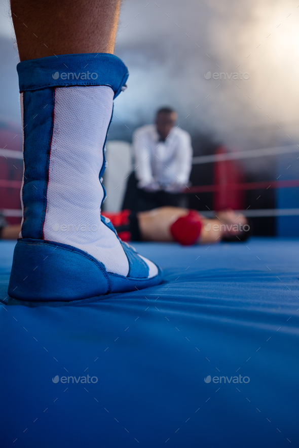 Low section of boxer standing against referee by athlete