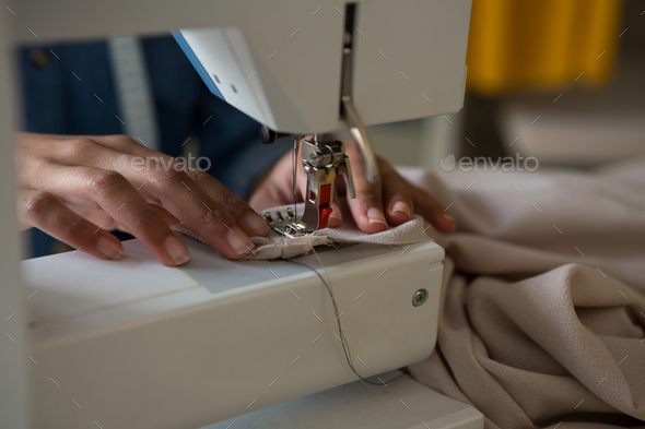 Professional dressmaker woman sews clothes on sewing machine at