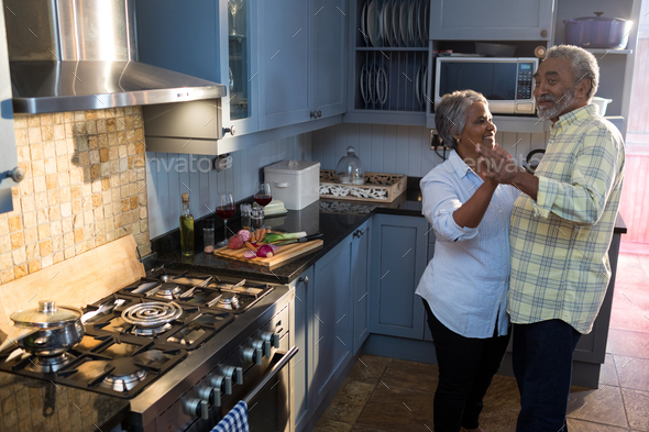 Smiling senior couple dancing in kitchen - Stock Photo - Images