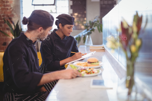 Young wait staff sitting with clipboard and food at counter