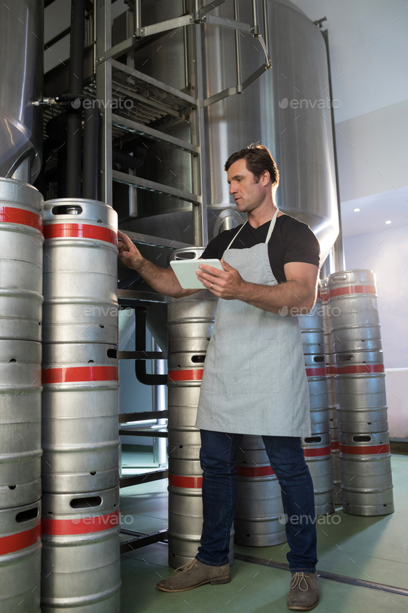 Full length of worker counting kegs at warehouse - Stock Photo - Images