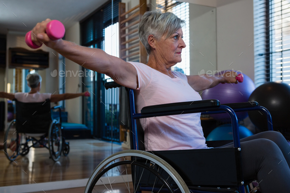 Senior woman in wheelchair performing exercise with dumbbell - Stock Photo - Images