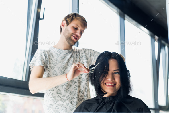 A woman in a hairdressing salon waiting to see the results looking in a mirror, smiling and talking
