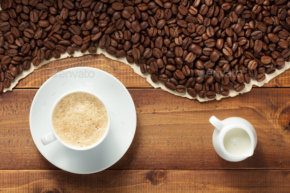 coffee beans and cup with milk on wooden background