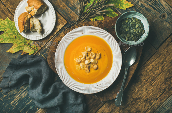 Warming pumpkin cream soup with croutons and seeds in plate - Stock Photo - Images