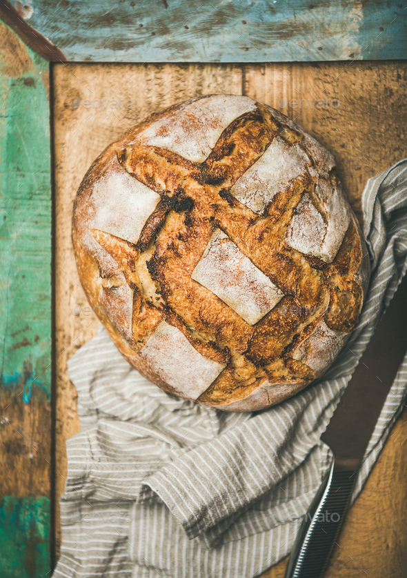 Flat-lay of sourdough wheat bread over rustic background - Stock Photo - Images