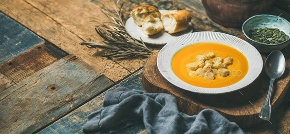 Warming pumpkin cream soup with croutons and seeds, wide composition - Stock Photo - Images