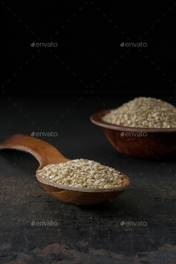 A wooden spoon and bowl of sesame seeds