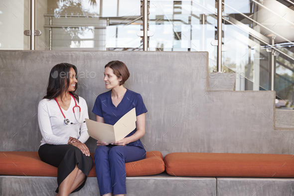 Two female healthcare workers discussing a medical record - Stock Photo - Images