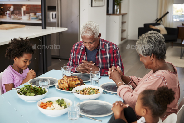 Grandparents Praying Before Meal At Home With Granddaughters - Stock Photo - Images