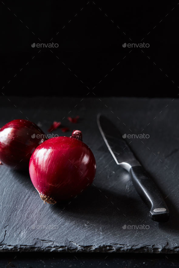 Red spanish onion with kitchen knife on slate backdrop - Stock Photo - Images