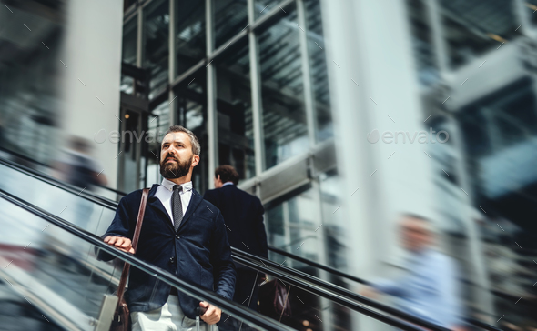 Hipster businessman using escalator in city, travelling to work. - Stock Photo - Images