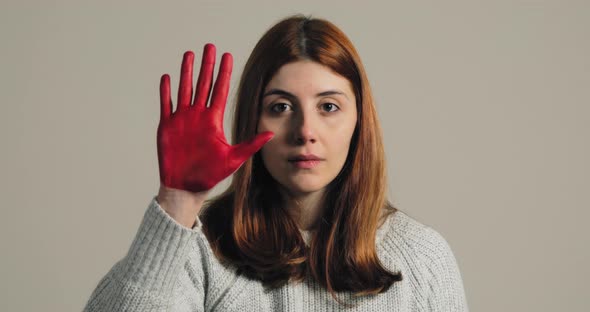 Sad Girl Raises Her Hand Painted Red to Stop and Protest Against Violence alt
