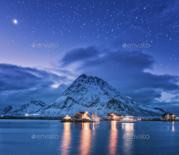Fishing boats near pier on the sea and snowy mountains at night - Stock Photo - Images