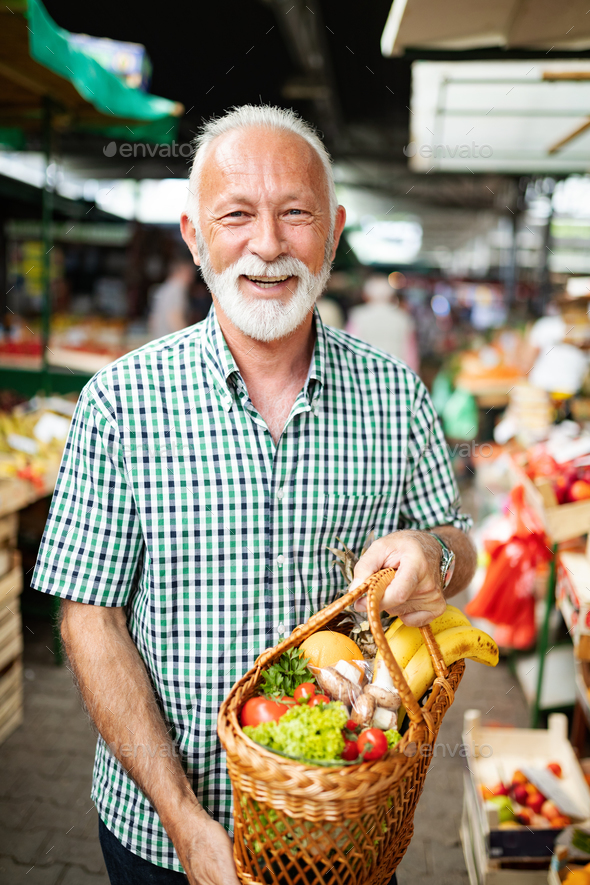 Handsome senior man shopping for fresh fruit and vegetable in a market Stock Photo by nd3000