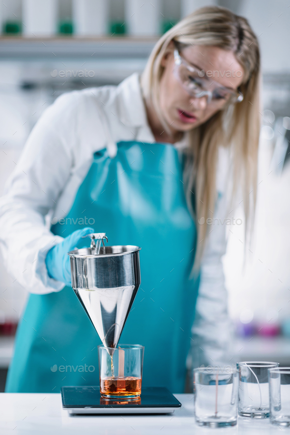 Female Candle Maker Pouring And Measuring Melted Orange Wax Stock Photo by  microgen