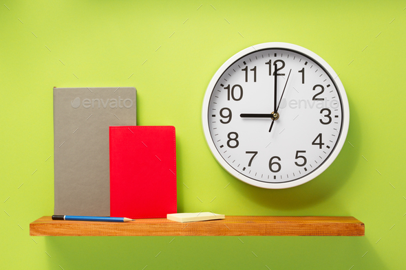 notebook and wall clock on shelf at wall background Stock Photo by seregam