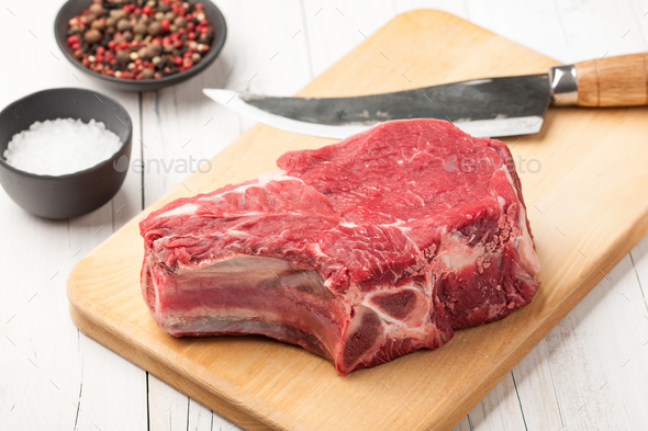 Raw beef meat with bone on cutting board Stock Photo by ff-photo