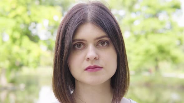 A Young Caucasian Woman Looks at the Camera in a Park  Face Closeup alt