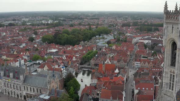 Passing Belfry of Bruges Belltower Revealing Cityscape and River, Aerial Forward alt