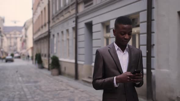 African Businessman Using Smartphone on Street alt