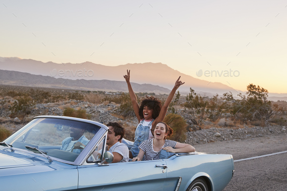 Group Of Friends On Road Trip Driving Classic Convertible Car Stock 