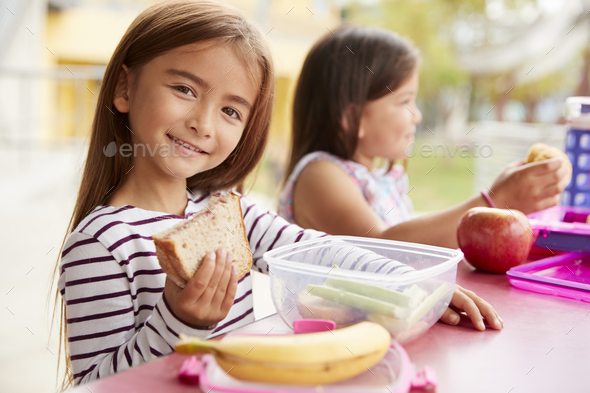 Elementary school girls eating at school lunch table