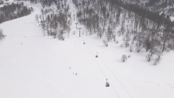 Flying over rope-way with gondolas at mountain resort Crystal Park in Bakuriani. Snowy winter day. alt