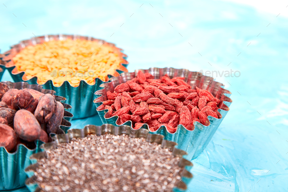 Various superfoods in small bowl on blue background - Stock Photo - Images