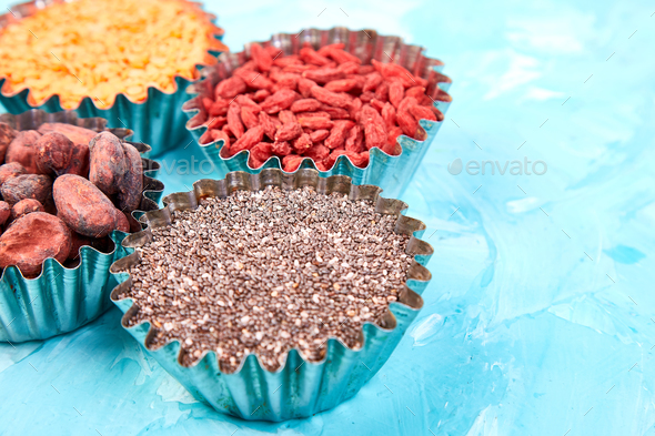 Various superfoods in small bowl on blue background - Stock Photo - Images