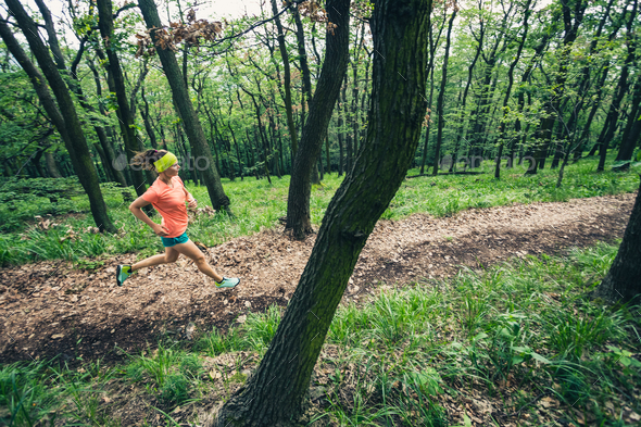 Young woman running in green forest. Endurance sport. - Stock Photo - Images