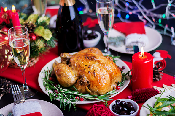 The Christmas table is served with a turkey, decorated with bright tinsel and candles - Stock Photo - Images