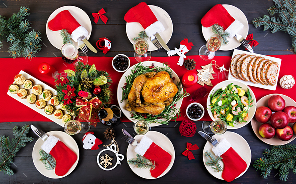 The Christmas table is served with a turkey, decorated with bright tinsel and candles - Stock Photo - Images