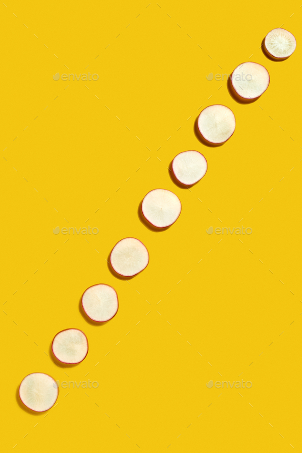 Spring diagonal pattern from fresh radish slices on a yellow background with copy space. Flat lay