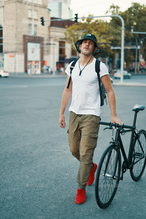 Portrait of young man walking with thoughtfully classic bicycle - Stock Photo - Images