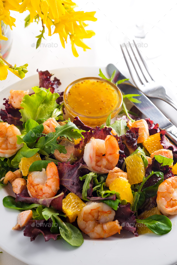 Healthy salad with prawns, lettuce, oranges and mango served on a plate with orange mustard sauce - Stock Photo - Images