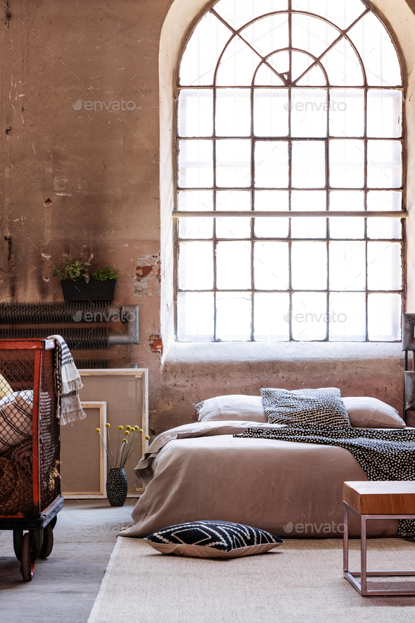 Real photo of an industrial bedroom interior with a big window a