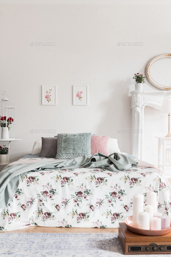 A comfortable bed with a rose pattern coverlet and fluffy pillow