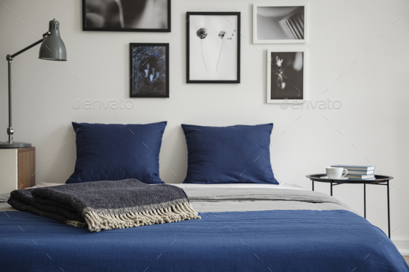 Close-up of bed with blue bedding and dark colored blanket. Beds - Stock Photo - Images