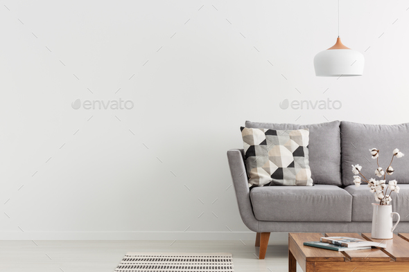 Flowers on wooden table and grey settee in white living room int - Stock Photo - Images
