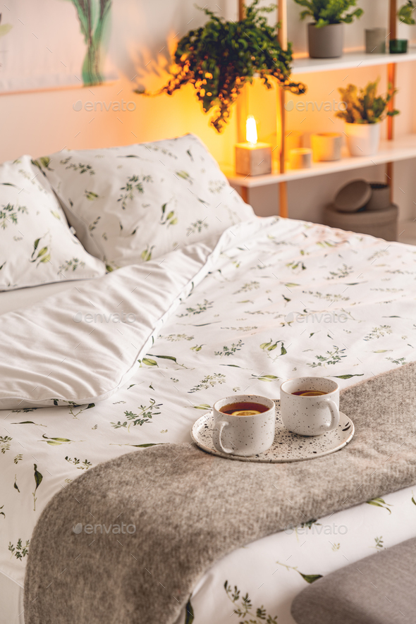 A mood created by a night lamp standing beside a bed dressed in - Stock Photo - Images