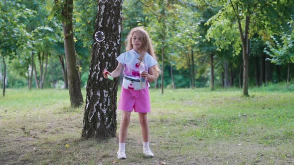 Little girl blowing bubbles. Girl blowing soap bubbles in the park alt