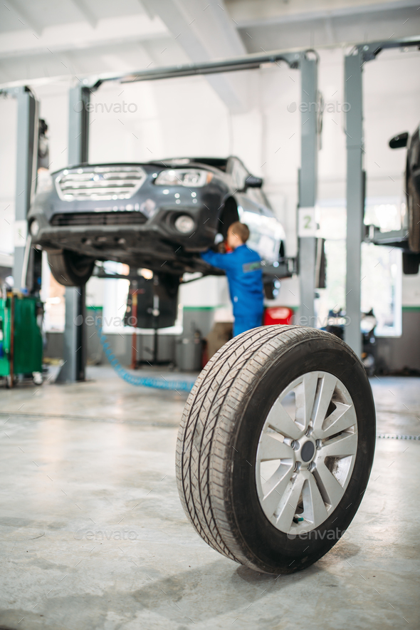 Wheel on the floor in tire service, car on lift - Stock Photo - Images