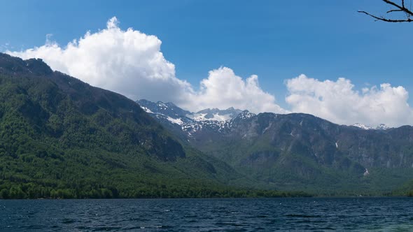 time lapse of white fluffy clouds forming over Lake Bohinj, Slovenia, between mountain range in Trig alt