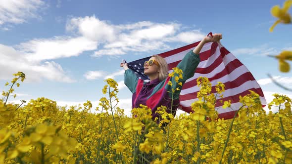 Woman with USA flag in yellow rapeseed field