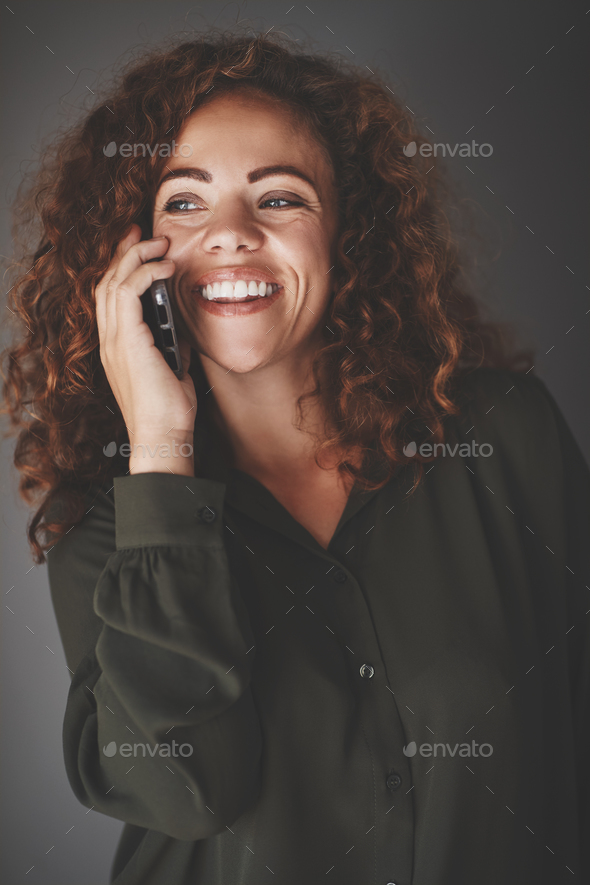 Young businesswoman talking on her cellphone against a gray background - Stock Photo - Images